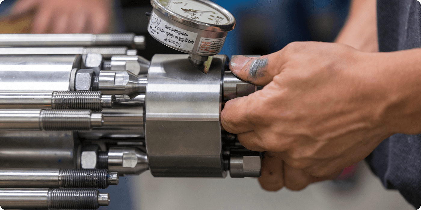 Hands performing maintenance on an Intensifier pump
